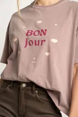 Remera color lila con estampa frontal de la frase 'Bon jour' con estrellas y labios.