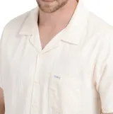 Camisa de manga corta color beige con cuello tipo cubano, cierre con botones y bolsillo en el pecho.