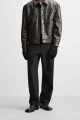 Pantalón negro de corte recto con cintura elástica, bolsillos delanteros y traseros. Cierre frontal con cremallera y botón.