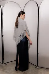 Chal triangular tejido de punto grueso color gris con flecos en los bordes.