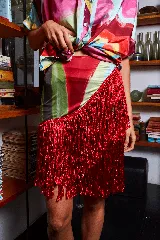 Falda corta tipo pareo con estampado abstracto multicolor y flecos de seda rojos en el ruedo.