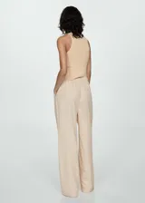 Pantalón de vestir color beige, de tiro alto, corte wide leg, con cintura elástica, pliegues frontales, cierre de cremallera y botón, y bolsillos laterales.