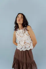 Blusa blanca de encaje con cuello redondo a la base y sin mangas.