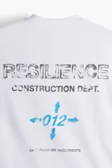 Remera deportiva blanca de corte boxy, confeccionada en tejido funcional DryMove™ que ayuda a absorber el sudor. Tiene cuello redondo ribeteado y hombros levemente caídos. Estampado en el frente con flechas y el número 012 en color celeste.