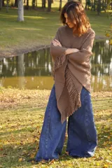 Poncho tejido en lana merino color marrón topo, con cuello redondo y terminación con flecos.