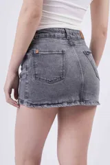 Minifalda de jean color gris oscuro desgastado, tiro medio/bajo, con cierre y botón frontal.