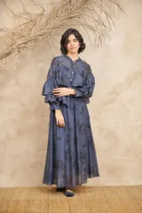 Conjunto azul con estampado floral negro, compuesto por una camisa de mangas largas con volados y una falda larga.