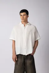 Camisa blanca de lino con cuello clásico, manga corta y cierre frontal con botones.