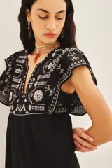 Vestido negro corto de corte amplio con bordados florales blancos en el frente, mangas y ruedo.