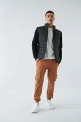 Campera negra con cuerpo acolchado de nylon y mangas de felpa. Tiene cuello alto, cierre frontal, bolsillos laterales con cierre, logo estampado en el pecho y logo de goma en la manga.