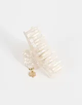 Broche para el pelo tipo pinza, color crema con efecto marmolado y charm colgante dorado con forma de trébol de cuatro hojas.