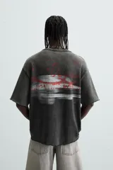Camiseta negra con efecto lavado, corte boxy fit, cuello redondo y manga corta. Estampado rojo en el frente.
