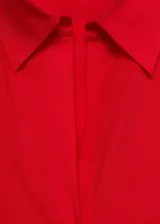 Camisa celeste de tejido fluido con cuello camisero, cierre frontal con botones y mangas largas con puños abotonados.