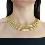 Gargantilla dorada con trama delicada que queda a la base del cuello.