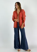 Saco de punto color crudo con cuello camisero, cierre frontal con botones y bolsillos de parche.