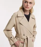 Trench coat largo color beige, de gabardina, con cuello con solapas, doble botonadura, lazo en la cintura, mangas largas con cintas en los puños y bolsillos delanteros.
