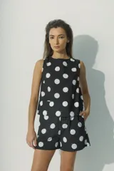 Top sin mangas color negro con estampado de lunares blancos. Corte holgado y cuello redondo.