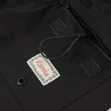 Boardshort negro con estampado en la pierna izquierda que incluye el texto "Rivvia" en naranja y un marco de flores verdes.