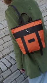 Mochila pequeña color borgoña con detalles en cuero marrón, asa de mano y correas ajustables.
