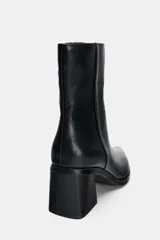 Botín de cuero negro con punta fina, cierre de cremallera lateral y tacón ancho geométrico.