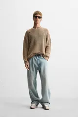 Sweater color marrón claro con efecto lavado ácido y roturas. De corte relajado, cuello redondo y mangas largas.