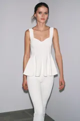 Top blanco de tejido elástico, con escote redondo, tirantes anchos y bajo peplum.