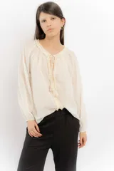 Blusa rosa de algodón con escote en V con cordones y detalle de volados.