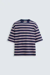Camiseta de hombre a rayas horizontales azul marino, blancas y rojas, de corte holgado, cuello redondo y mangas cortas.