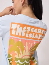 Remera negra de algodón con corte holgado y estampado frontal con el texto "Rusty Australia Mermaid Beach" en colores naranja, verde y amarillo.