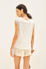 Musculosa blanca de lino con detalle de encaje en mangas y cuello. Tiene bordado de alas en el bajo.