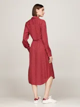 Vestido camisero midi rojo con estampado geométrico blanco, cuello camisero, manga larga con puños abotonados, cinturón anudable y abertura frontal.