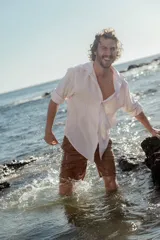 Camisa de lino color blanco con finas rayas verticales rosas, de corte clásico, manga corta y cuello italiano.