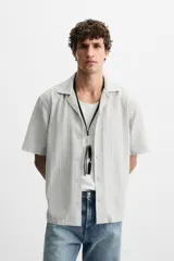 Camisa de manga corta con cuello bowling y corte relaxed fit, confeccionada en tejido con algodón y diseño a rayas verticales en tonos beige y blanco.