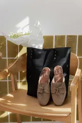 Mocasines tipo mule color beige, con detalle de cordones y ojales metálicos.