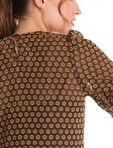 Blusa peplum marca Nanette, color negro con estampado de lunares dorados. Tiene escote a la base, mangas cortas con frunce y abertura con botón en la espalda. Incluye una musculosa interna a tono.