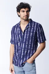 Camisa de manga corta para hombre confeccionada en viscosa, con estampa de arabescos en color azul y blanco. Presenta cuello con solapa y cierre frontal mediante botones.