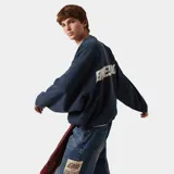 Buzo oversize azul con un diseño gráfico en la espalda y cuello redondo.
