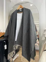 Ruana gris con diseño de espiga y flecos color crema en el borde inferior.