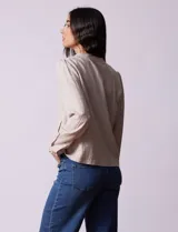 Chaqueta color beige de lino y rayón, con cuello mao, cierre frontal con botones y bolsillos delanteros.