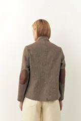 Chaqueta corta con cuello solapa, manga larga con coderas aplicadas, cierre frontal con botones y bolsillos ojal. Con forro.