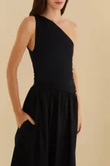 Vestido largo negro con un solo hombro, corte ajustado en el torso y falda acampanada.