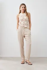 Pantalón de lino color beige con cintura elastizada con cordón ajustable, corte recto y pespuntes verticales al frente.