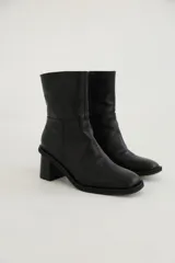 Bota de cuero negra con diseño moderno y tacón bajo, ideal para un estilo rocker y chic.
