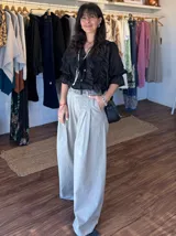 Pantalón de jean celeste de corte ancho con pinzas en la cintura y cinturón plateado con apliques florales.