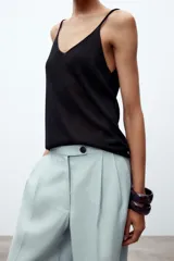 Pantalón de tiro medio color celeste confeccionado en hilatura con mezcla de lyocell. Tiene bolsillos laterales, pinzas delanteras, pierna ancha y cierre frontal con cremallera y botón.