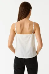 Musculosa blanca de algodón con breteles finos y escote cuadrado con detalle de puntilla.