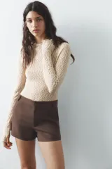 Shorts tiro bajo color negro con bolsillos delanteros. Cierre frontal con cremallera y ganchos metálicos.