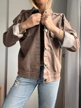 Campera de corte clásico color marrón, con detalles desgastados y cuatro bolsillos frontales.