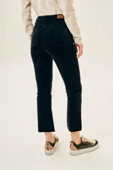 Pantalón de pana negro, tiro medio, corte ajustado hasta la rodilla y acampanado en la parte inferior, con terminación desflecada.