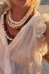 Conjunto de blusa y short color blanco. La blusa es de gasa plisada con volados en las mangas y botones de nácar en la parte delantera. El short es de gasa con cintura elastizada.